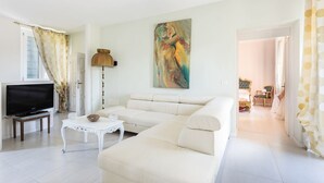 Un salon moderne avec un canapé, un téléviseur et une lampe.