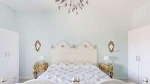 Une chambre à coucher avec un grand lit, deux tables de chevet, un lustre et deux armoires.