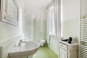 A bathroom with a white sink, toilet, and shower area.