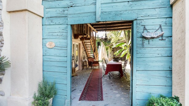 Une entrée rustique en bois, avec un tapis rouge menant à un espace repas comprenant une table et des chaises.