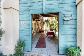 A rustic wooden entrance with a red carpet leading to a dining area with a table and chairs.