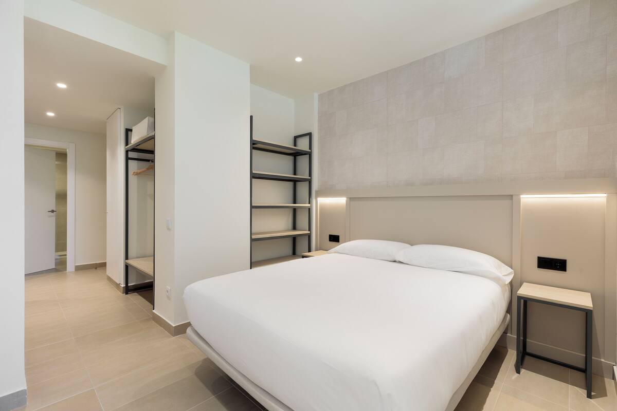 Une chambre à coucher moderne avec un grand lit, des étagères intégrées et un dressing.