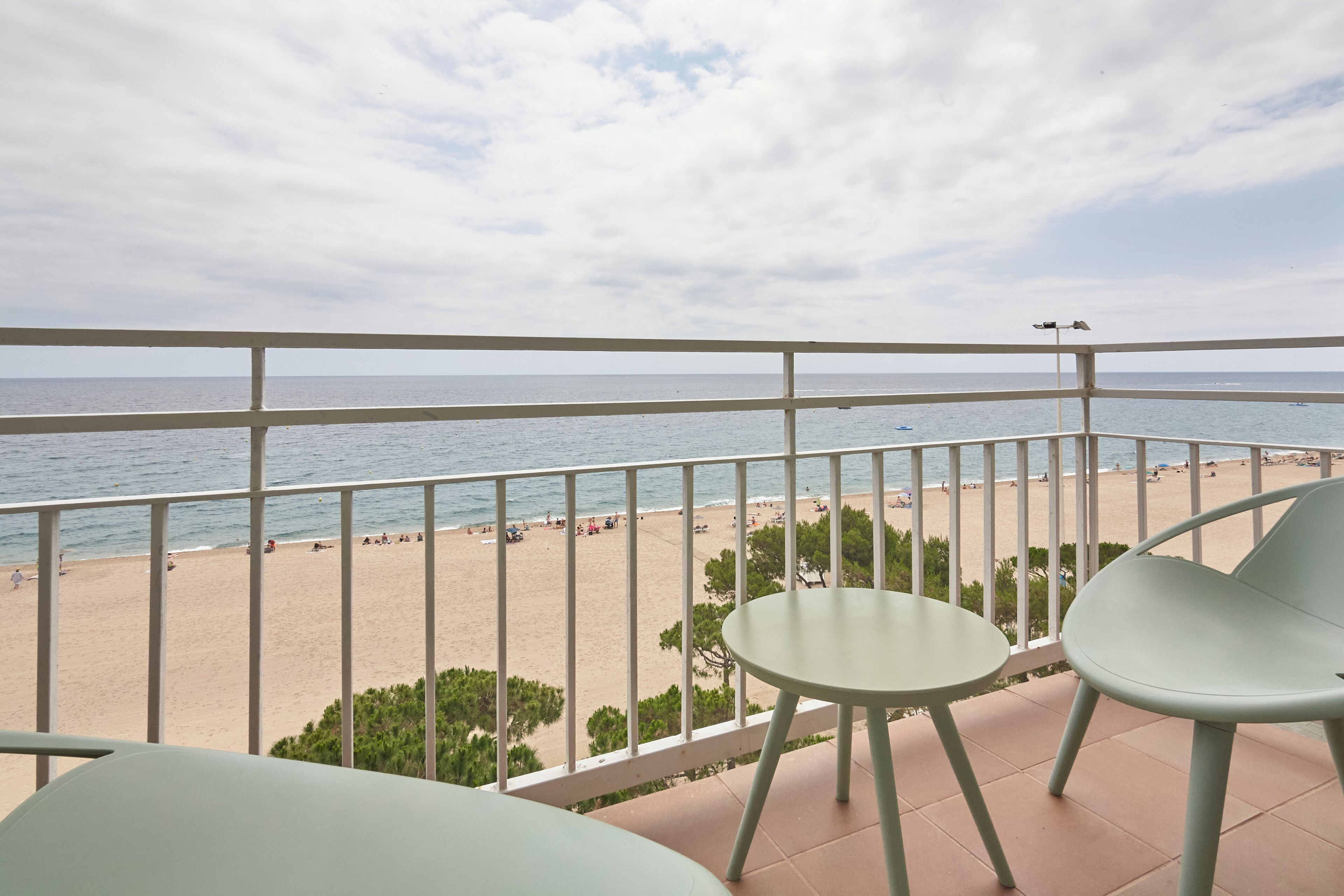 A balcony with a view of a beach and a clear sky.