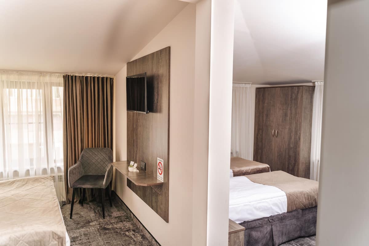 A hotel room with a bed, a desk, a chair, a TV mounted on the wall, and a wardrobe.