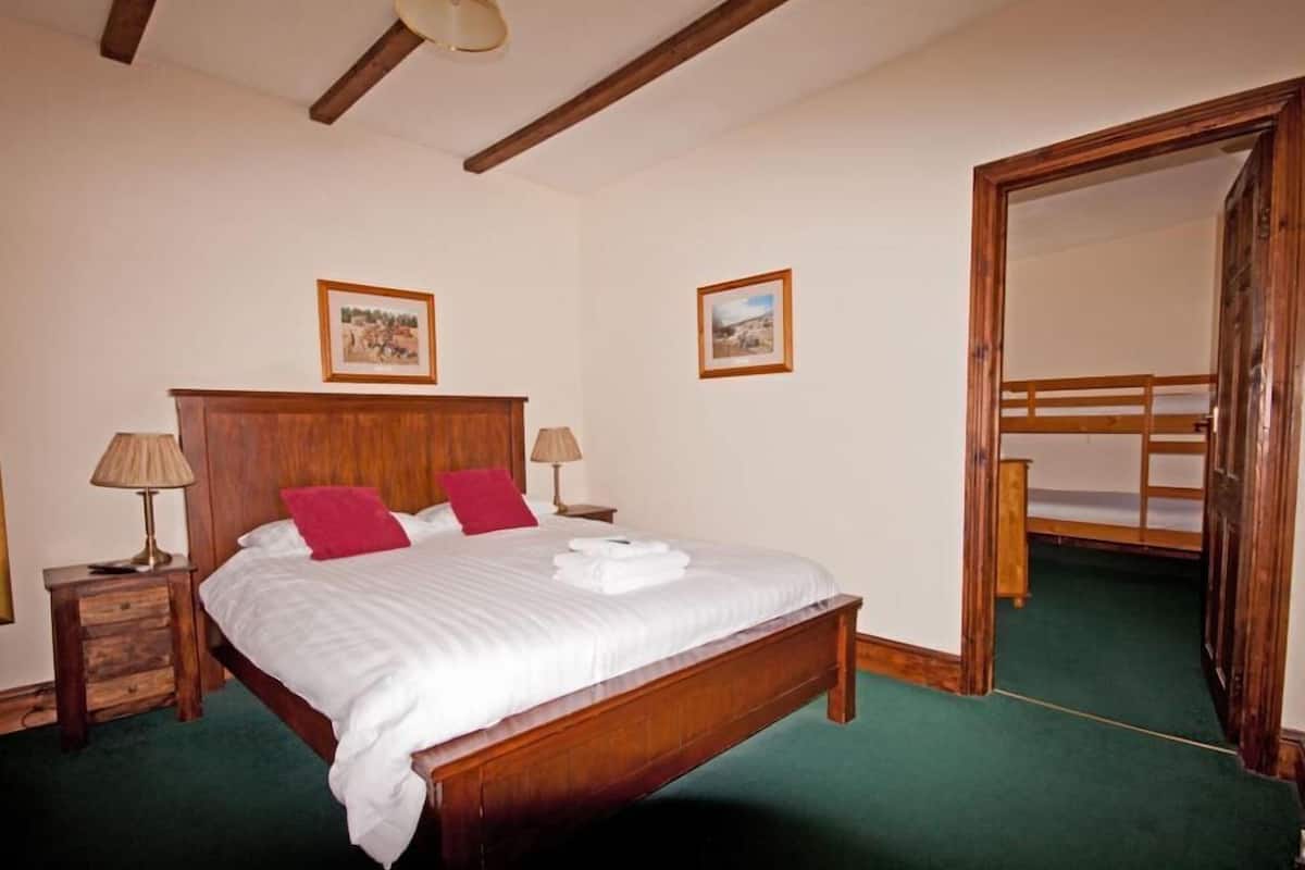 Quarto com cama de madeira, duas mesas de cabeceira, duas luminárias e duas quadros na parede.
