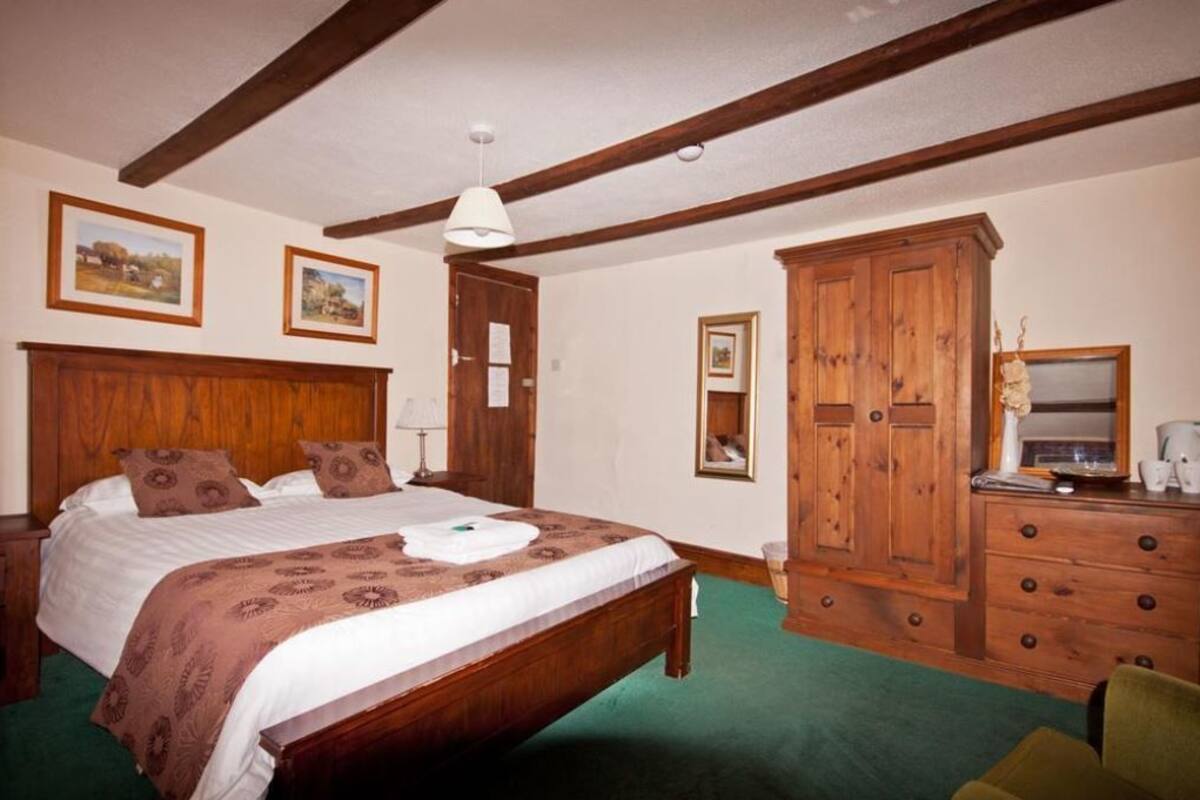 Quarto com cama de madeira, penteadeira e espelho.