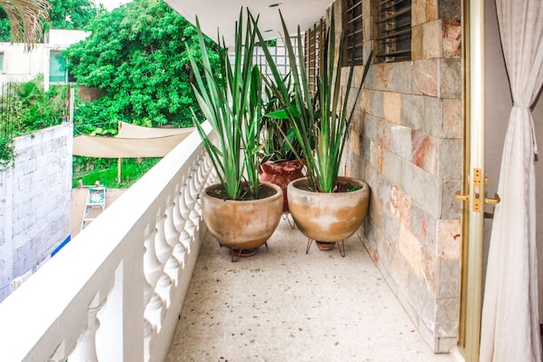 A balcony with two potted plants, a white railing, and a stone wall. - Villa Mandarina Suites Tuxpan (Tuxpan)