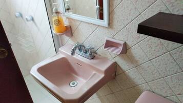 A bathroom with a pink sink, a mirror, and a toilet.
