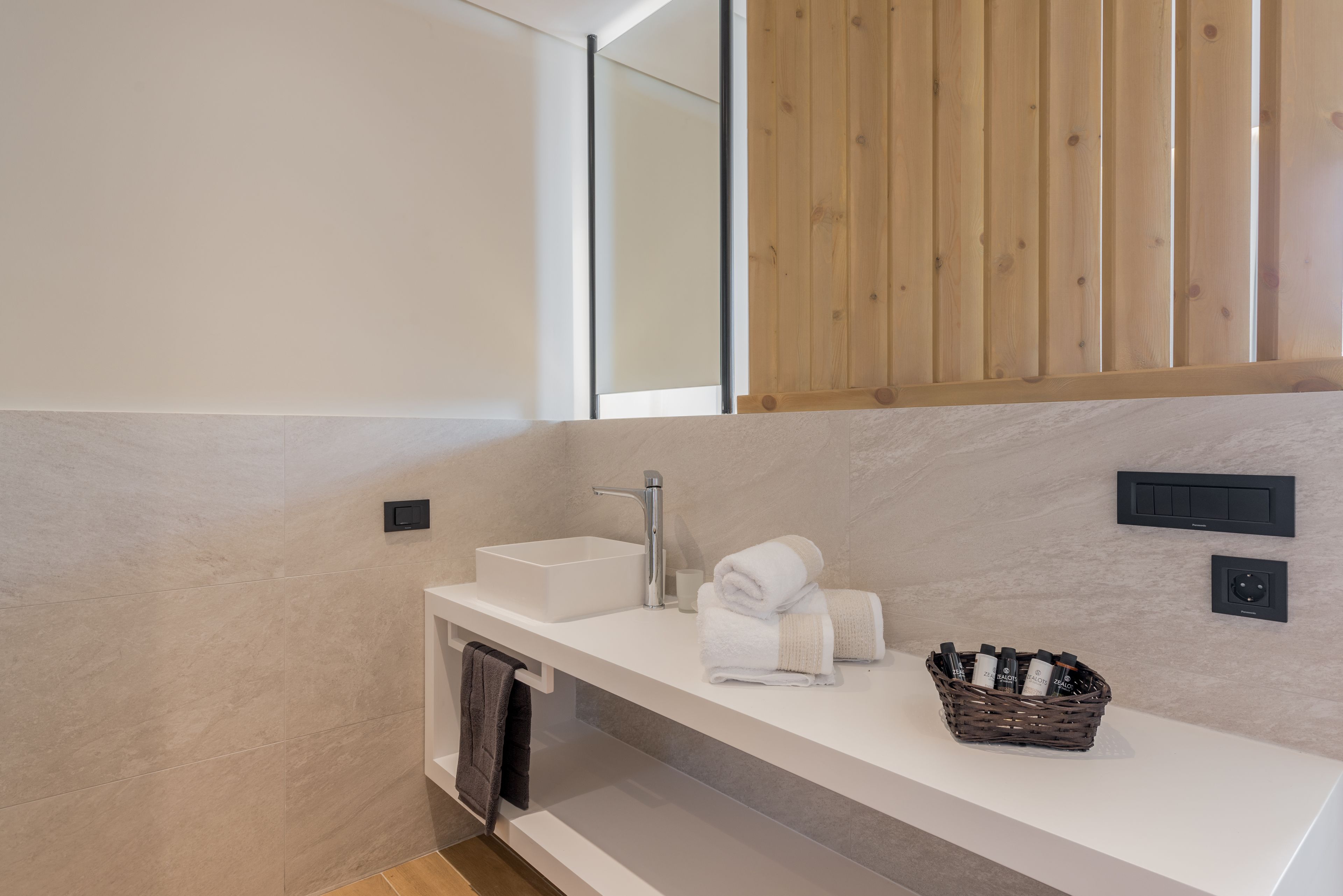 Un baño moderno con un lavamanos blanco, un espejo y un revestimiento de pared de madera.