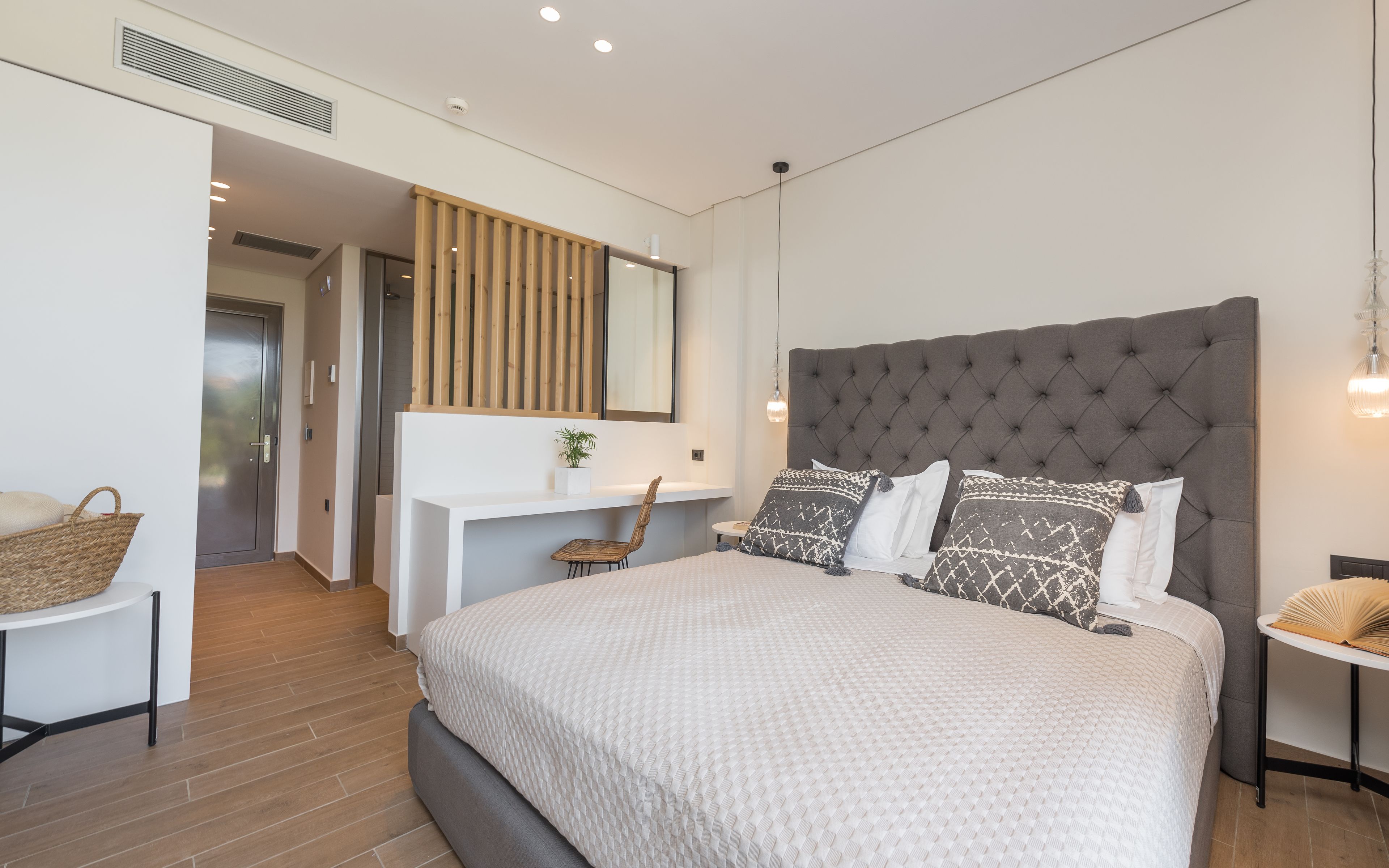 Un dormitorio moderno con una cama grande, una mesita de noche, una silla y un escritorio con un espejo.