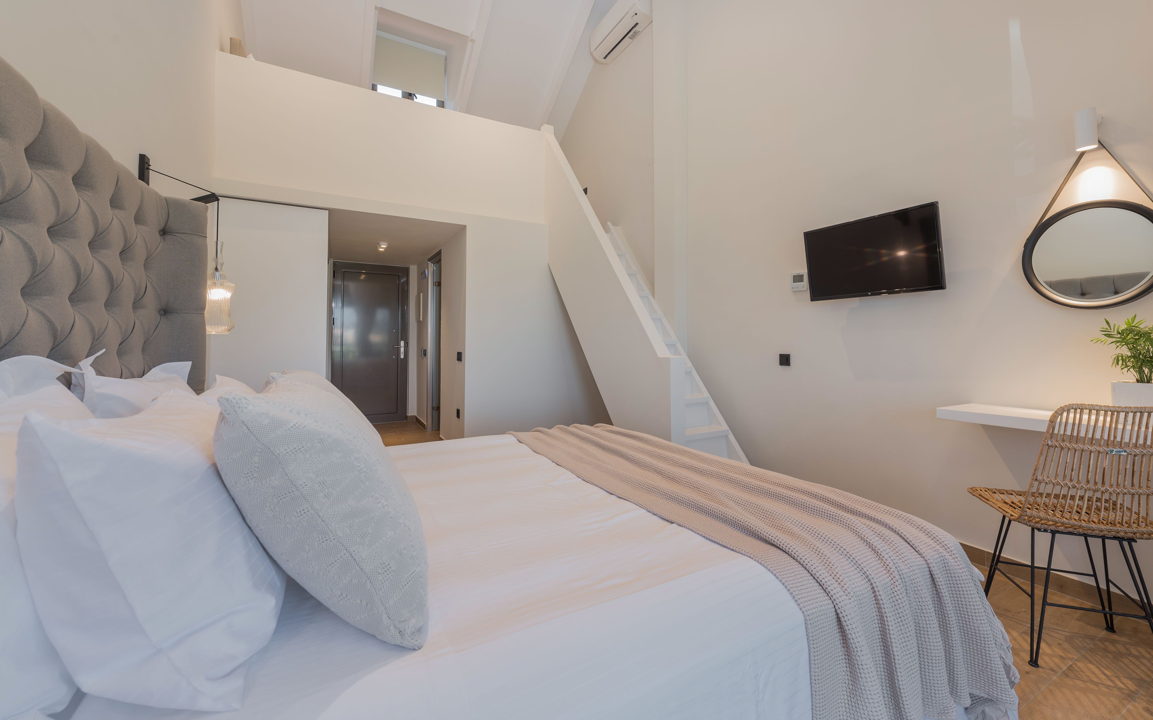 Une chambre moderne avec un grand lit, une télévision, un bureau et une chaise.