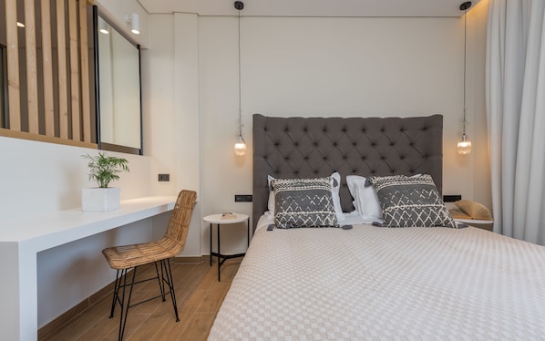 Un dormitorio moderno con una cama grande, una mesita de noche, una silla y una pequeña mesa redonda.