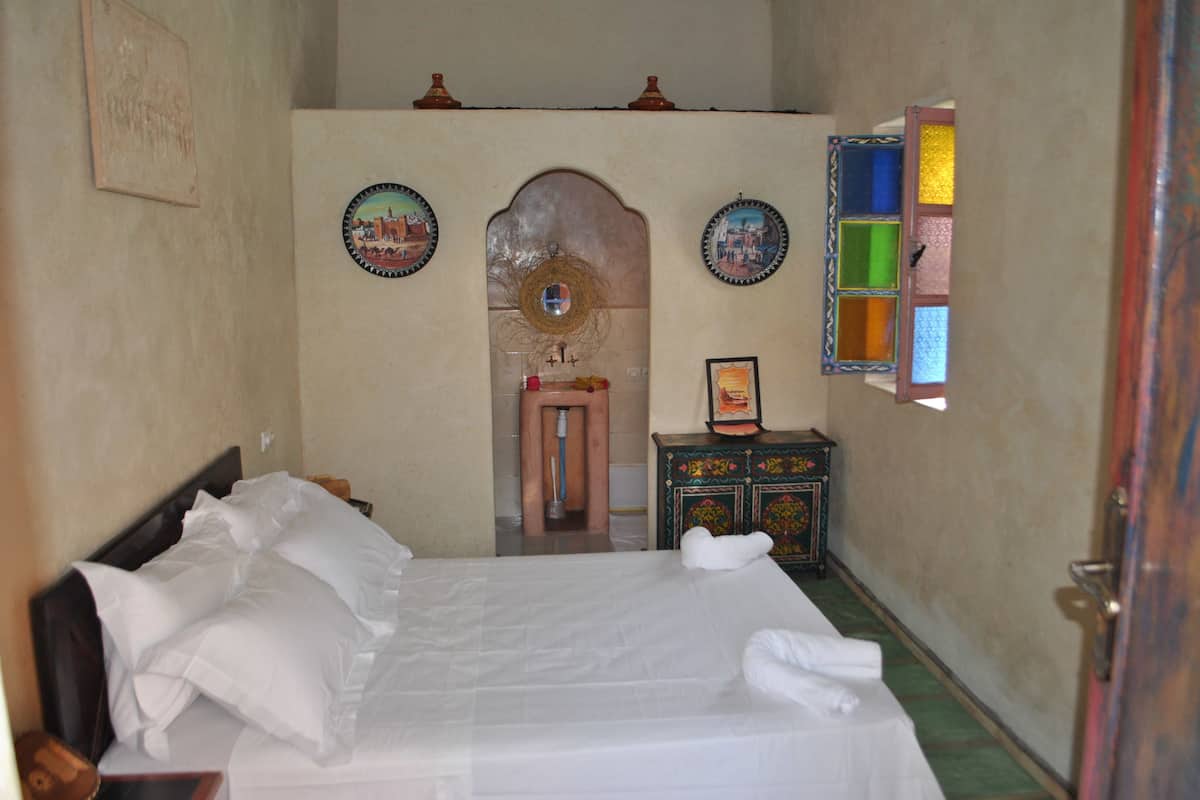A hotel room with a bed, a small table, a mirror, and a wall with decorative plates.