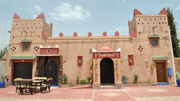 A traditional Moroccan building with a central archway, two towers, and a sign reading "Kasbah Darla". - Auberge Kasbah Darla (Aghouatim)