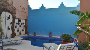 A pool area with lounge chairs, potted plants, and lanterns. - Auberge Kasbah Darla (Aghouatim)
