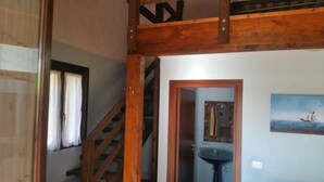 A wooden staircase with a metal handrail, a door leading to a bathroom, and a painting on the wall. - Agriturismo Vita e Natura (Noto)