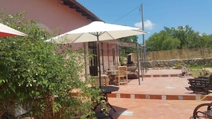 An outdoor patio with a covered seating area, a fire pit, and a stone wall in the background. - Agriturismo Vita e Natura (Noto)