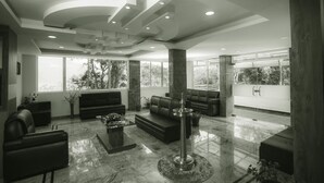 Un hall amplio y moderno con techos altos, ventanas grandes y una zona de estar central.