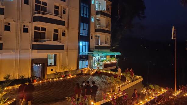 Un hotel de varios pisos con balcones, un espacio al aire libre cubierto con plantas y una entrada bien iluminada.