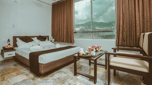 Un dormitorio con cama, mesita de noche, silla y ventana con cortinas.