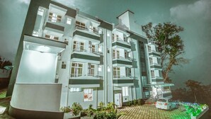 Un hotel de varios pisos con balcones y un área de estacionamiento.