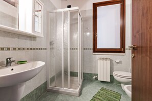 A bathroom with a shower enclosure, sink, toilet, and a mirror with a wooden frame. - Peschiera - Martiri del Lavoro (Peschiera del Garda)