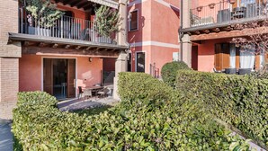 Un immeuble à plusieurs étages doté de balcons, d’un patio avec des espaces pour s’asseoir à l’extérieur et de haies bien entretenues.