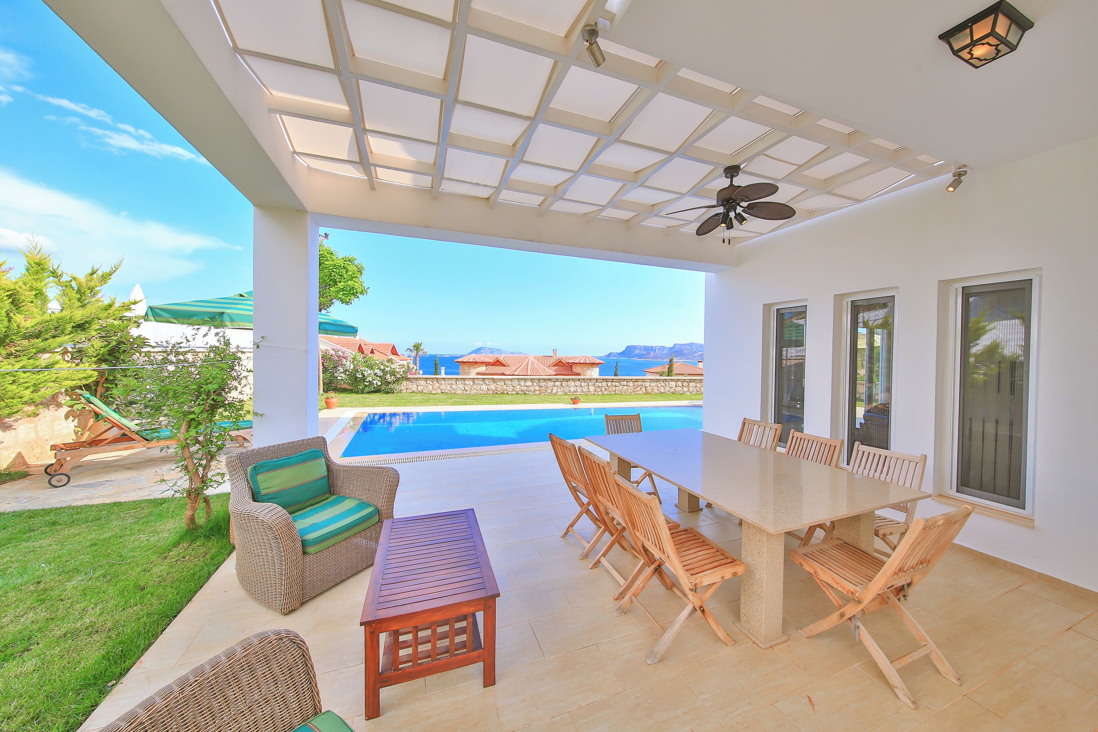 Une terrasse extérieure avec une piscine, des meubles en osier et une table.