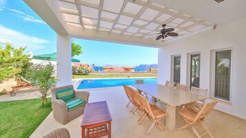 Une terrasse extérieure avec une piscine, des meubles en osier et une table.