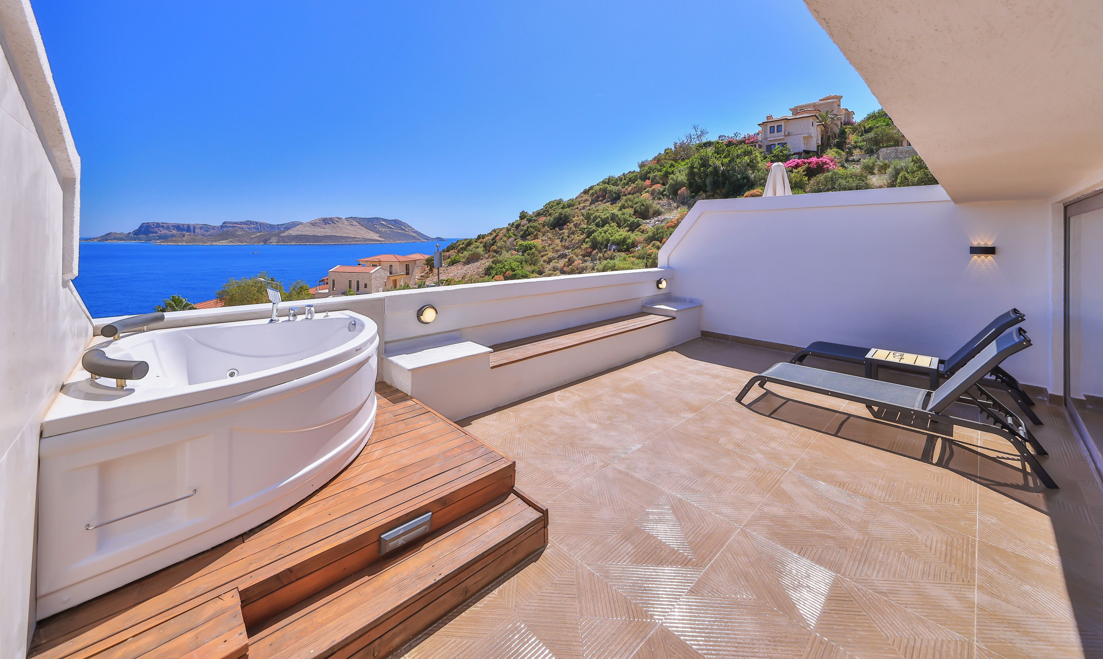 Ein Balkon mit Whirlpool, Holzstufen und Liegestuhl.