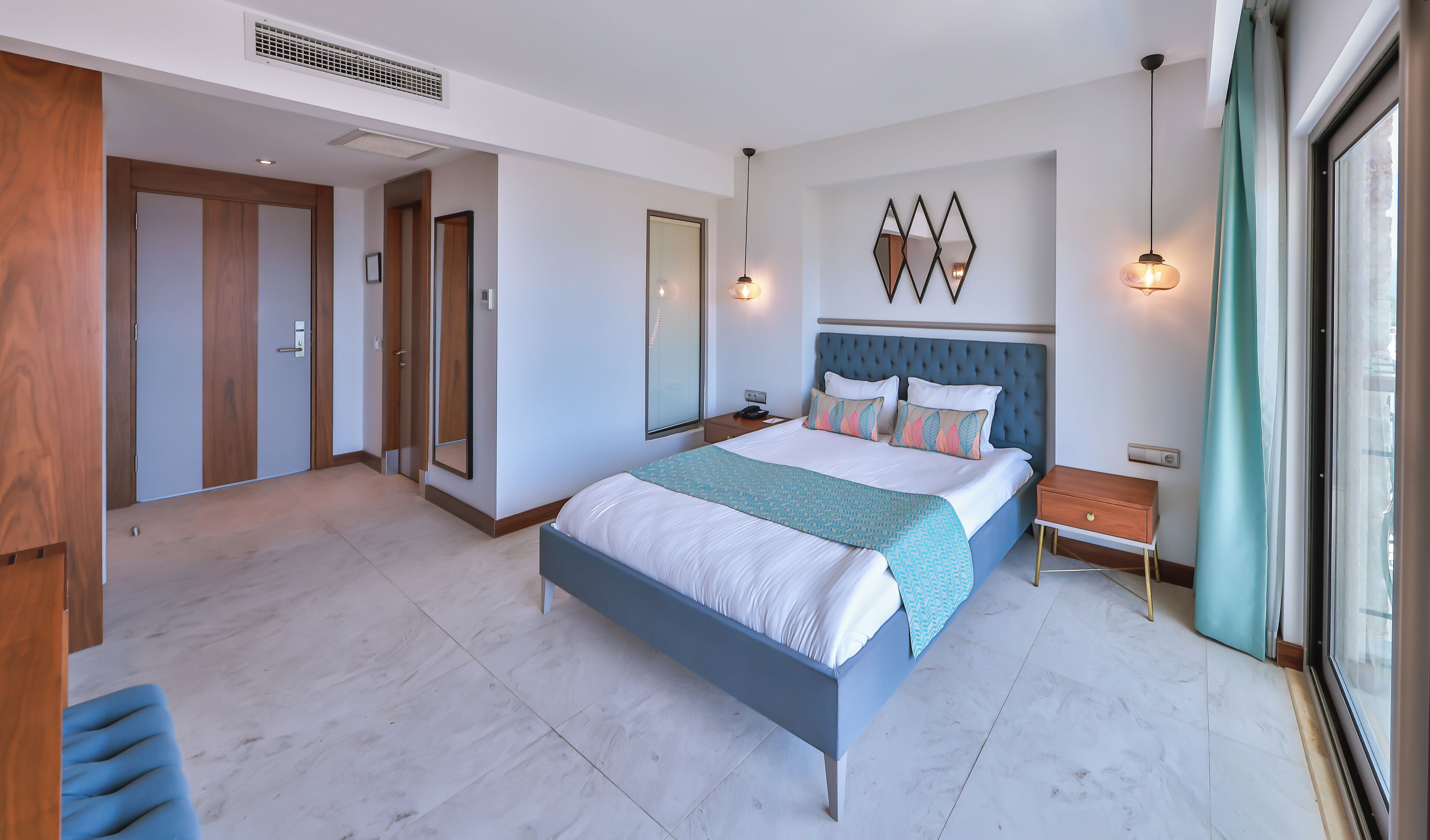 A modern bedroom with a large bed, a nightstand, a dresser, and a window with curtains.