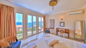 A hotel room with a large bed, a desk, a chair, and a view of the sea. - Molino Hotel (Kas)