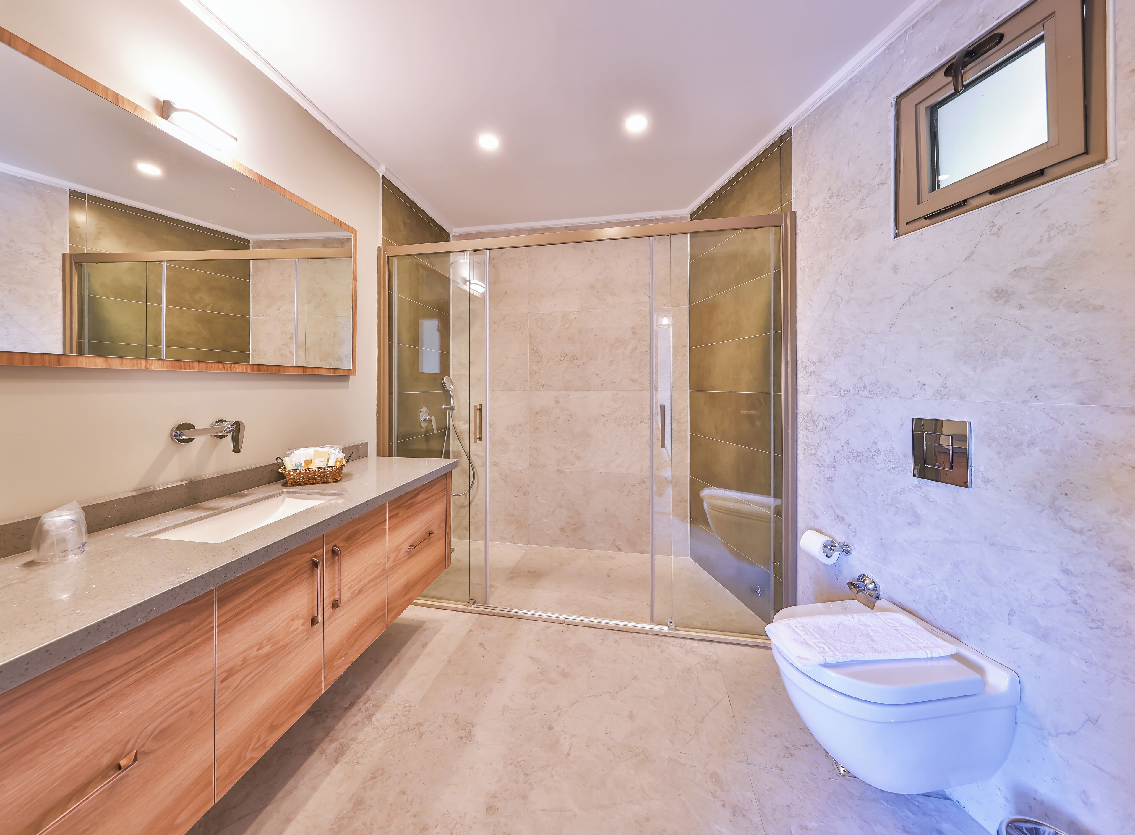 A modern bathroom with a glass-enclosed shower, a wooden vanity, and a large mirror.