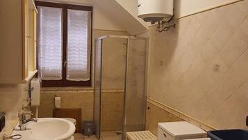 Ein kleines Badezimmer mit Waschbecken, Toilette, Dusche und Waschmaschine.