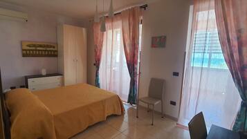 Ein Schlafzimmer mit Bett, Stuhl, Schreibtisch und Kleiderschrank.