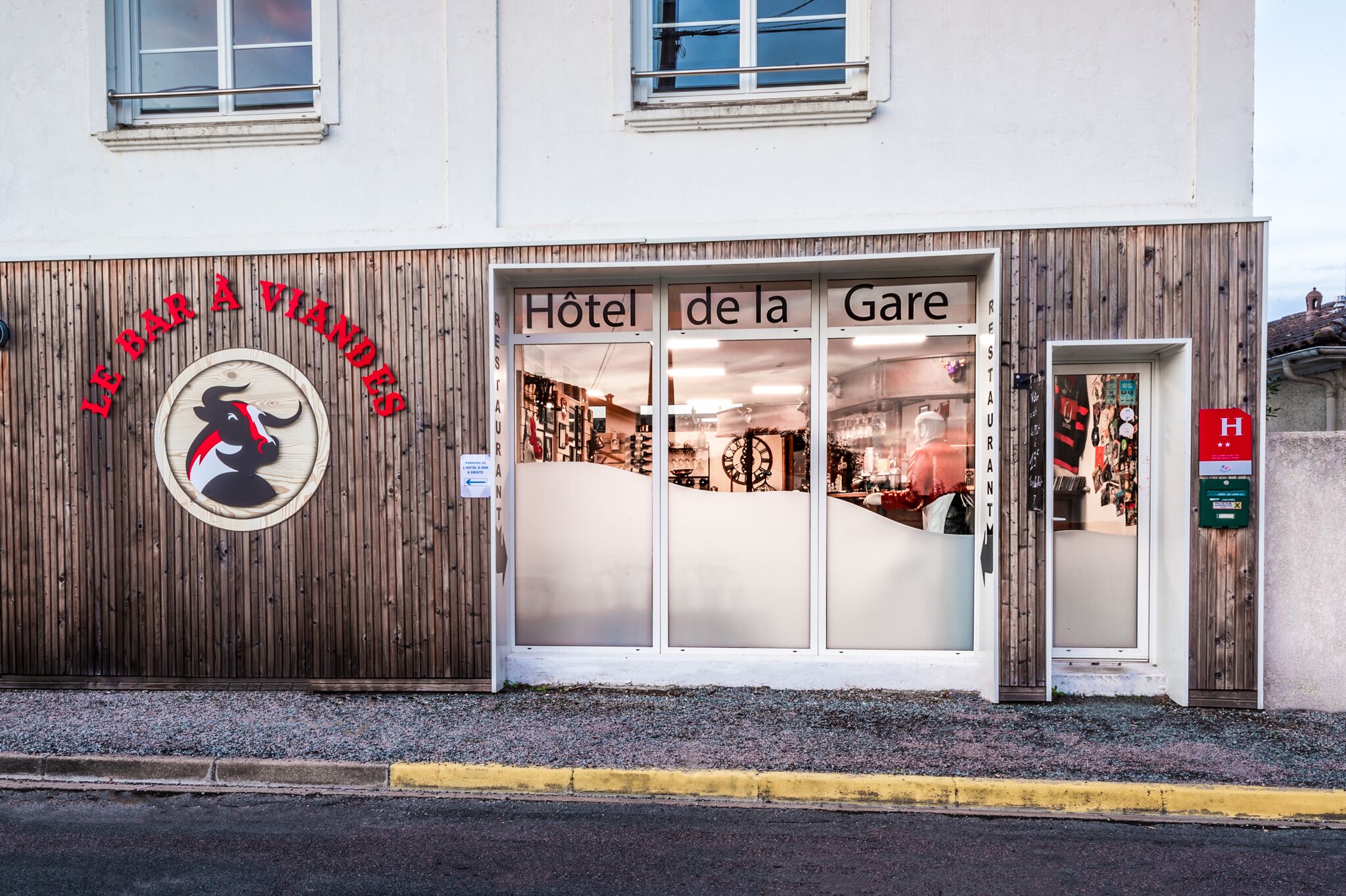 A hotel facade with a wooden exterior and a sign reading "Hôtel de la Gare".