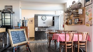 Een gezellig restaurant met houten vloeren, een krijtbordmenu en een rustieke inrichting, inclusief oude keukenbenodigdheden.