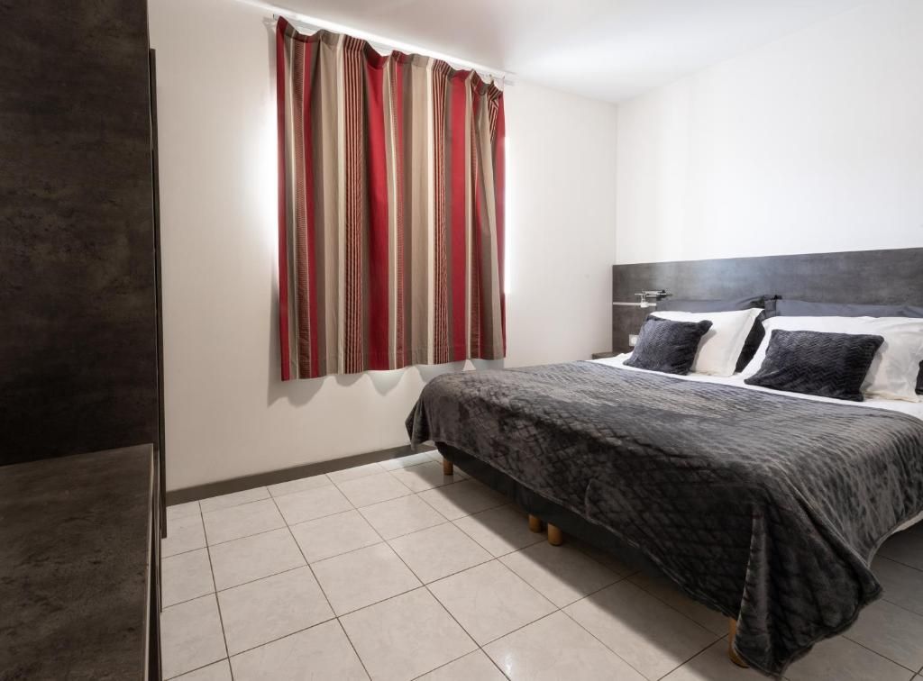 Un dormitorio con cama, cortinas y cabecero.