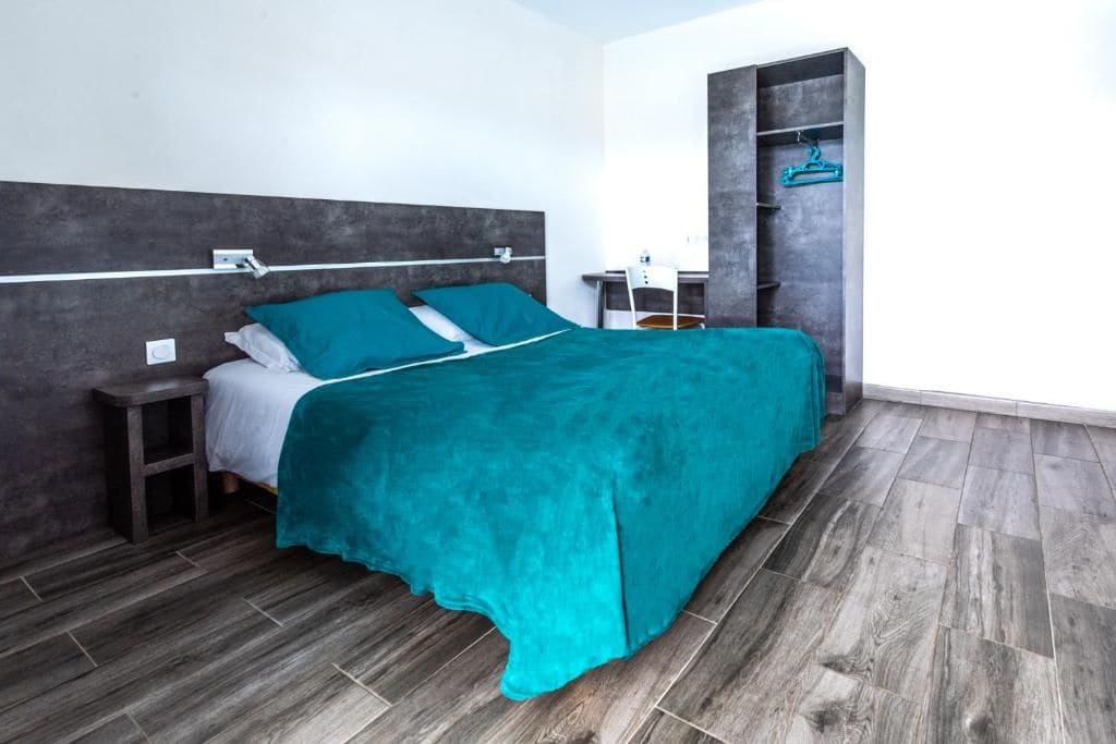 A modern bedroom with a bed, nightstands, a desk, and a wardrobe.