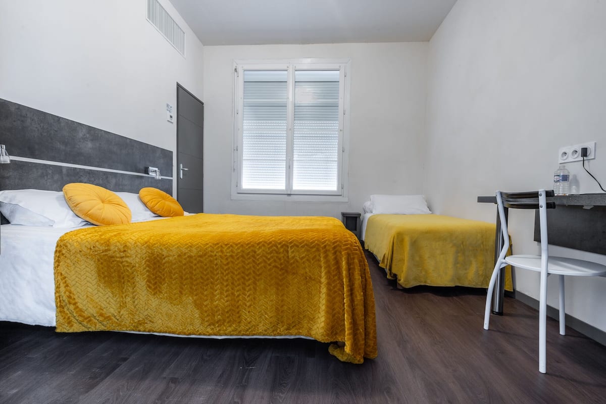 A hotel room with two beds, a desk, and a chair.