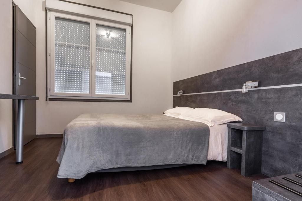 A bedroom with a bed, a window, a bedside table, and a wardrobe.