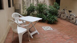 A patio with a white table and chairs, surrounded by potted plants and a bicycle. - Vicenza - Stradella San Giovanni 7 (Vicenza)