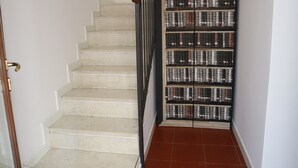 A staircase with a wooden handrail and a wall-mounted display of books. - Vicenza - Stradella San Giovanni 7 (Vicenza)