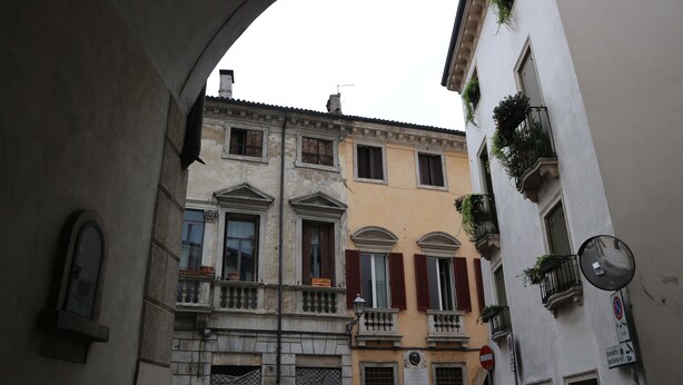 An arched passageway between buildings with a clock and a no parking sign. - Vicenza - Stradella San Giovanni 7 (Vicenza)