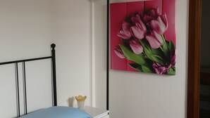 A bedroom with a bed, a nightstand, a wall-mounted lamp, and a painting of pink tulips. - Vicenza - Stradella San Giovanni 7 (Vicenza)