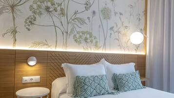 Een hotelkamer met een bed, een klein rond tafeltje, een wandlamp en een stopcontact.