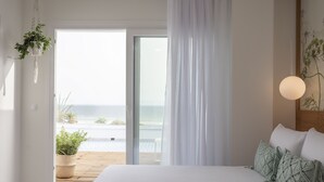 Een slaapkamer met een bed, een hangende plant, uitzicht op de oceaan en een balkon met beplanting.