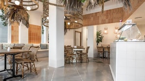 Een modern interieur met een eethoek, voorzien van rieten meubels en een centrale witte tafel.