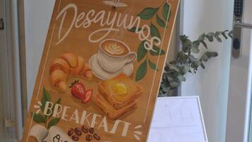Un cavallet de fusta amb un cartell amb temàtica de l'esmorzar que anuncia 'Desayunos' de les 8:00 a les 11:00.