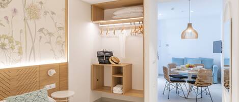 A modern bedroom with a bed, a small table, a wardrobe, and a dining area with chairs and a table.